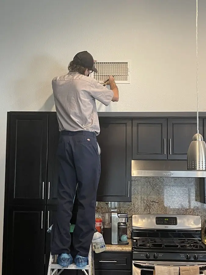 Technician inspecting an air vent during HVAC service in California Polytechnic State University
